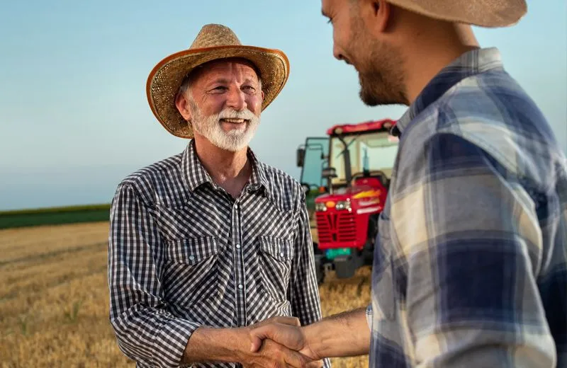 two farmers shaking hands on a farm